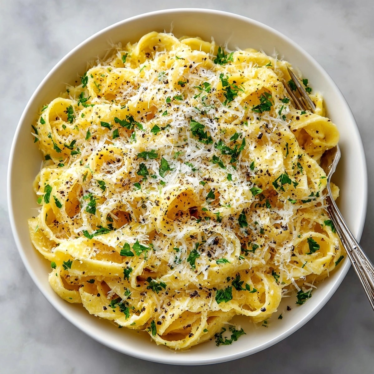 Steaming noodles tossed in garlic butter and Parmesan cheese, sprinkled with cracked black pepper.