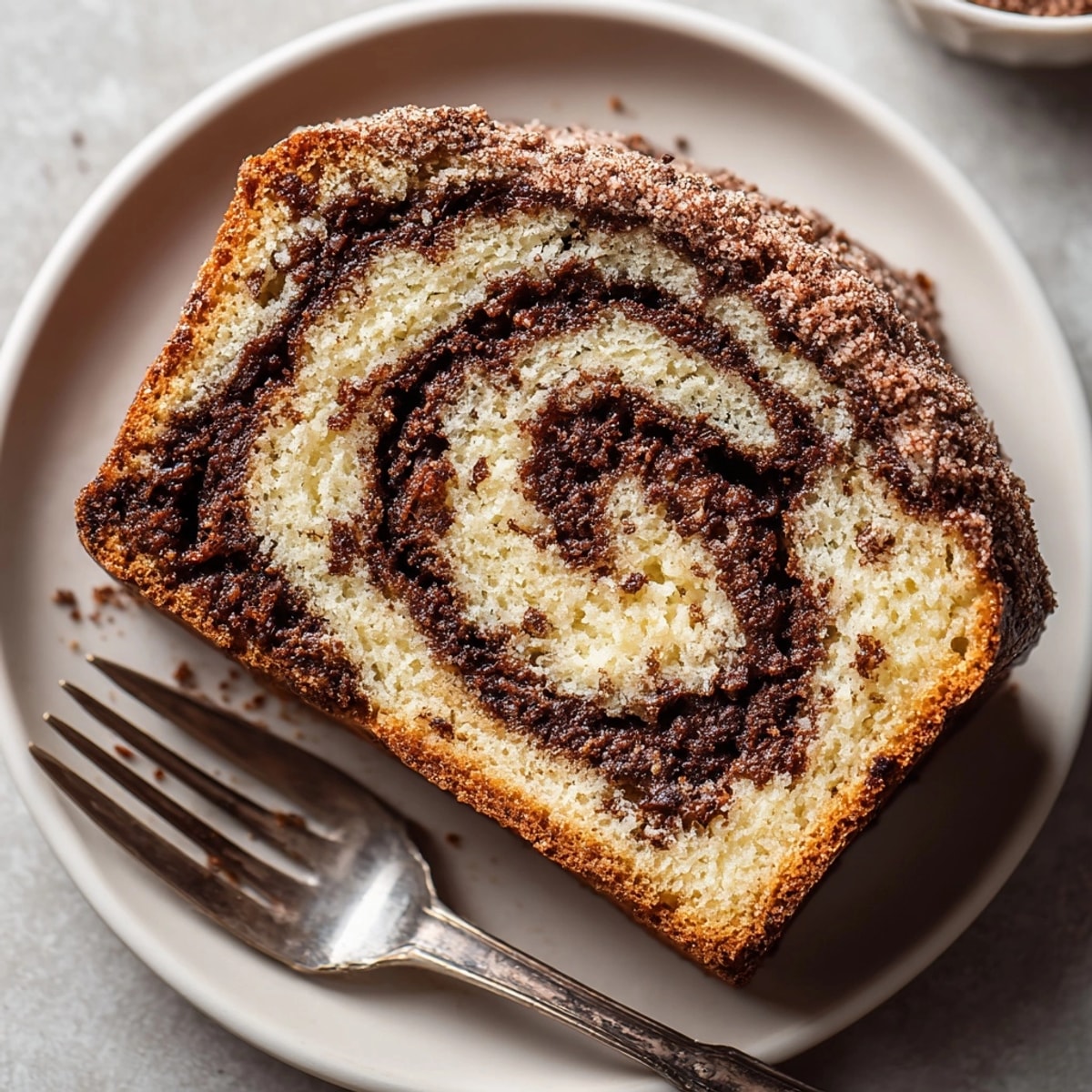 Golden-brown Chocolate Cinnamon Swirl Bread loaf dusted with cinnamon sugar, served warm for a cozy breakfast treat.