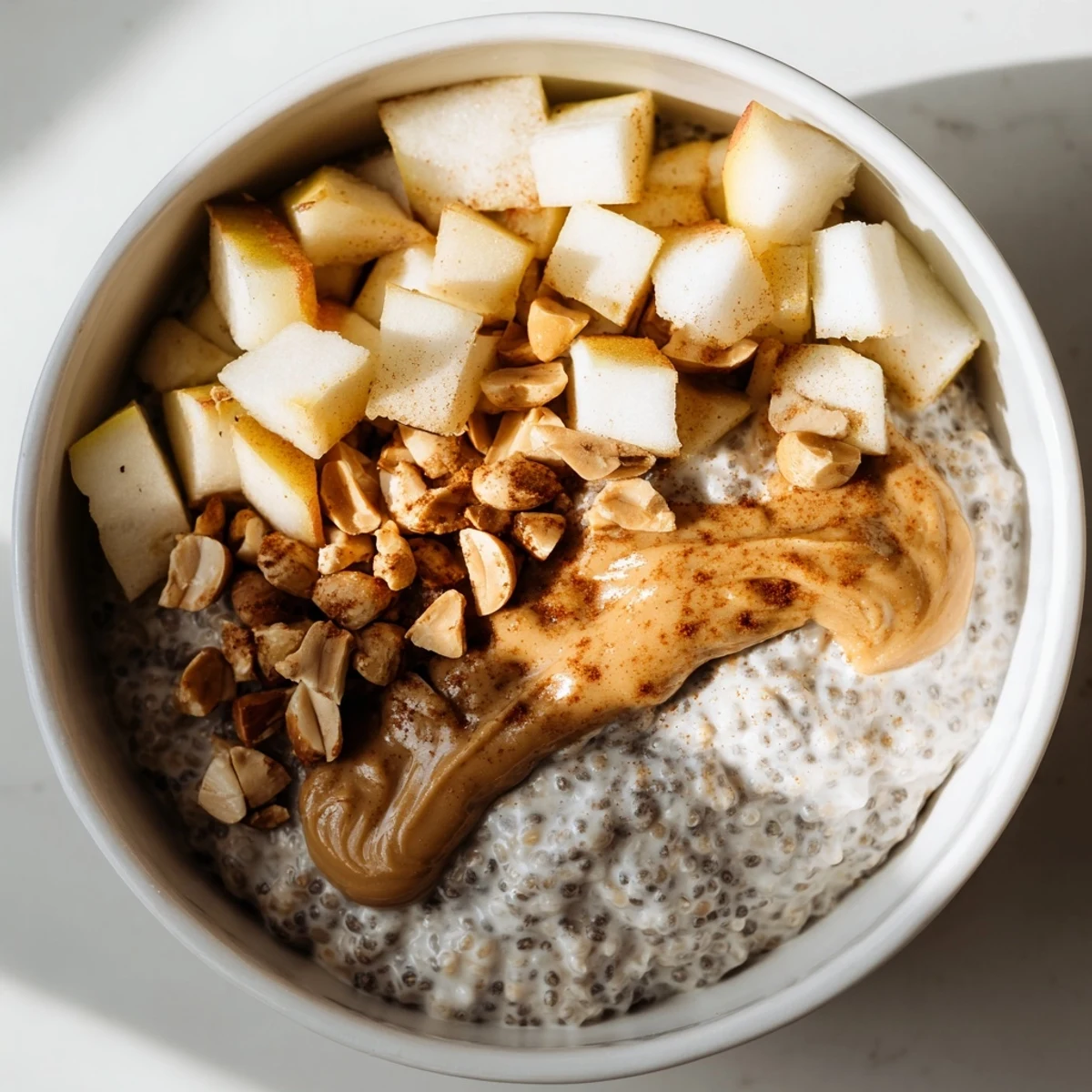 A close-up of Apple-Chia Pudding, a layered breakfast parfait with fresh apple and peanut butter.