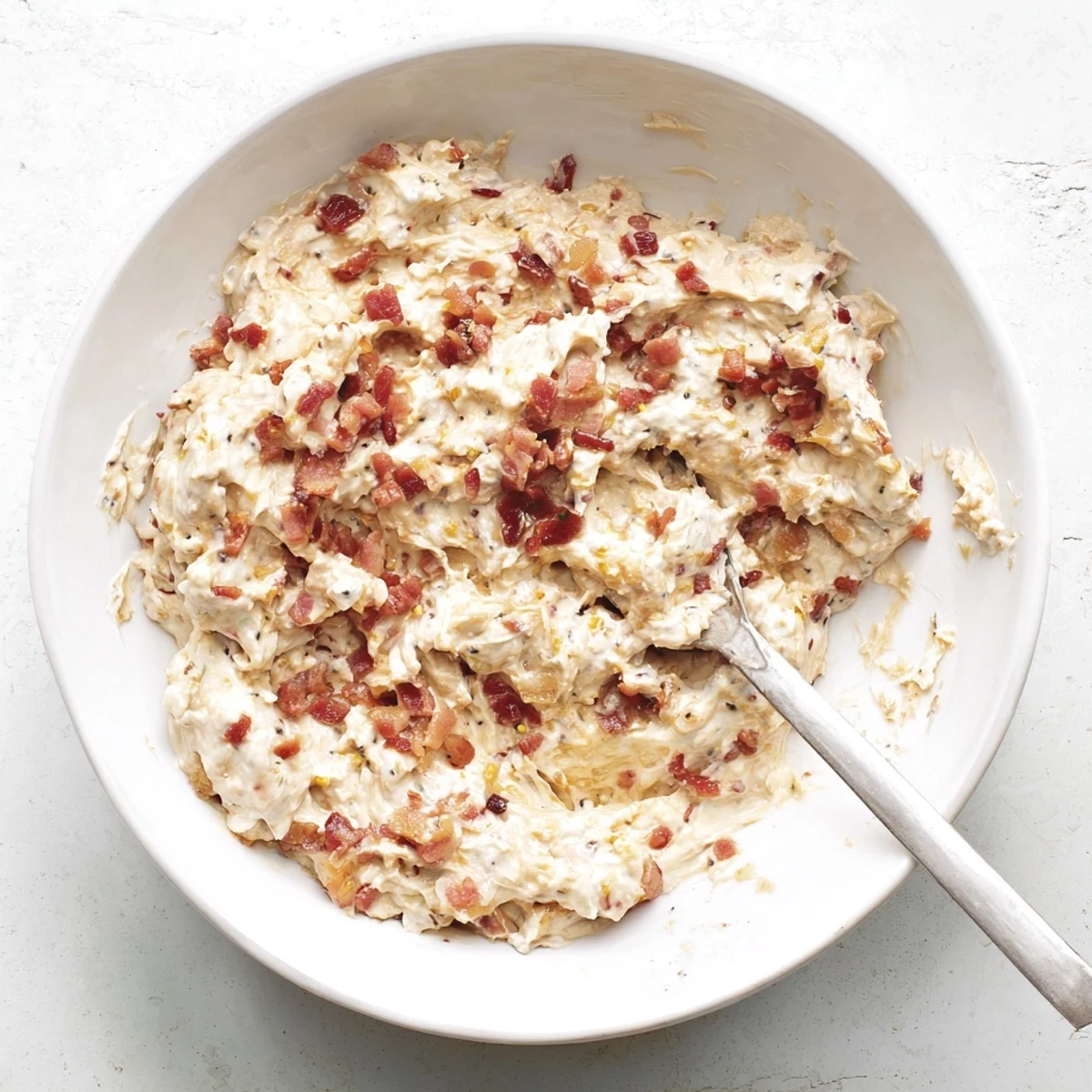 Close-up shot shows creamy Caramelized Onion and Bacon Dip, perfect for dipping crackers at a party.