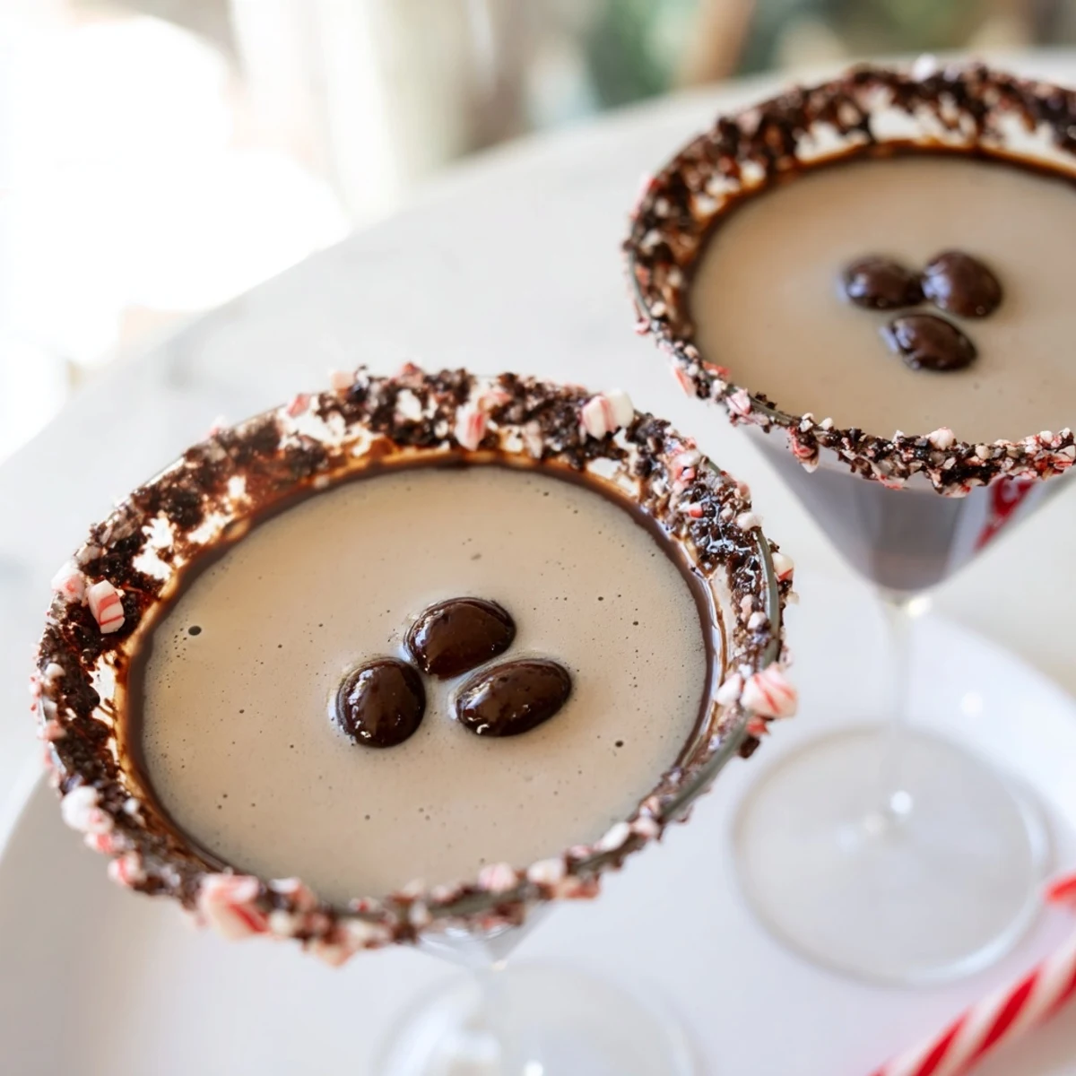 Festive Peppermint Espresso Martini in a glass with a chocolate peppermint rim, garnished with coffee beans.