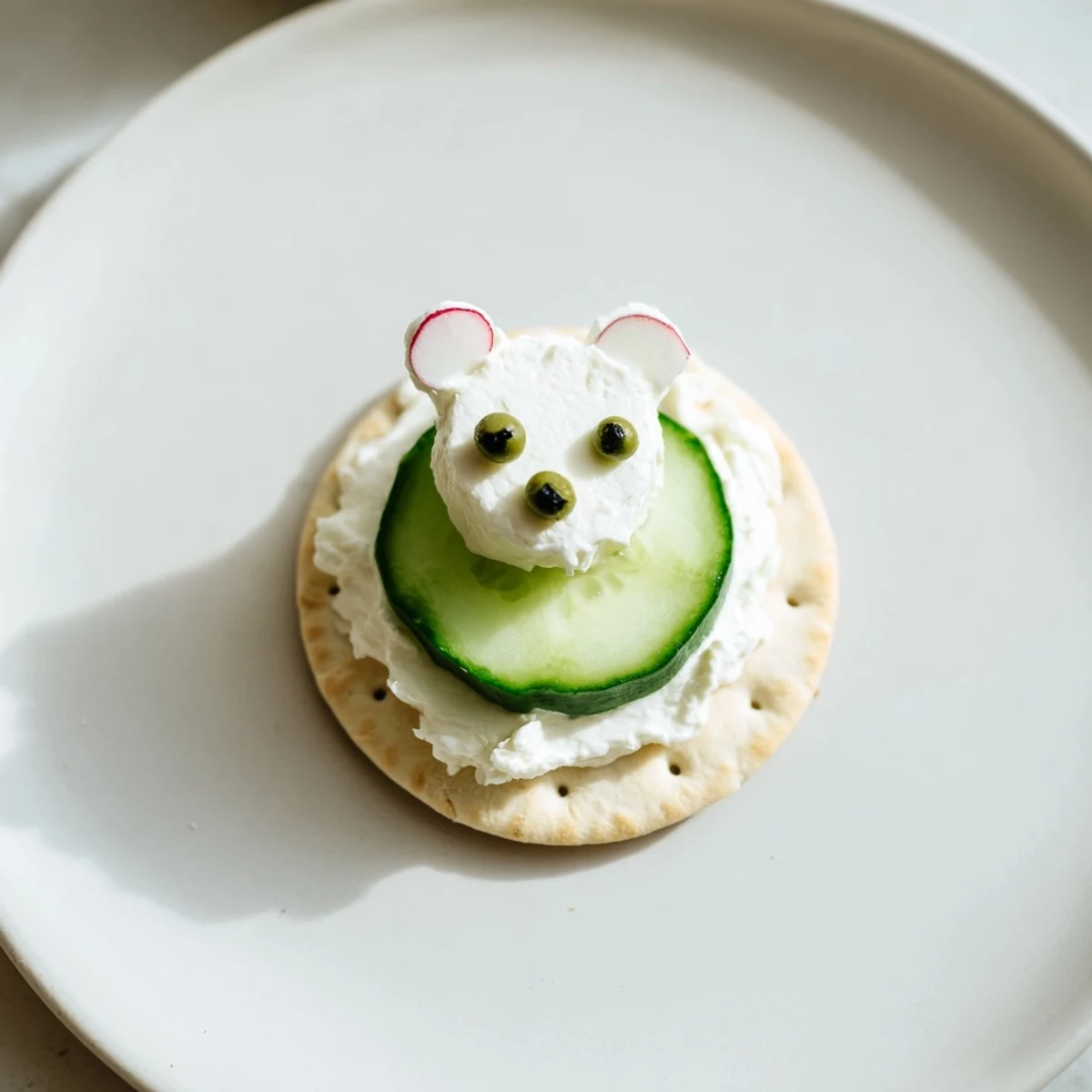 Polar Bear Iceberg Cracker Stacks: Creamy cream cheese "polar bears" atop crisp cucumber "icebergs," ready to serve.