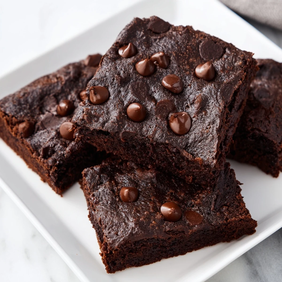 Warm, fudgy Greek yogurt brownies topped with melted chocolate chips, ready to slice and serve.