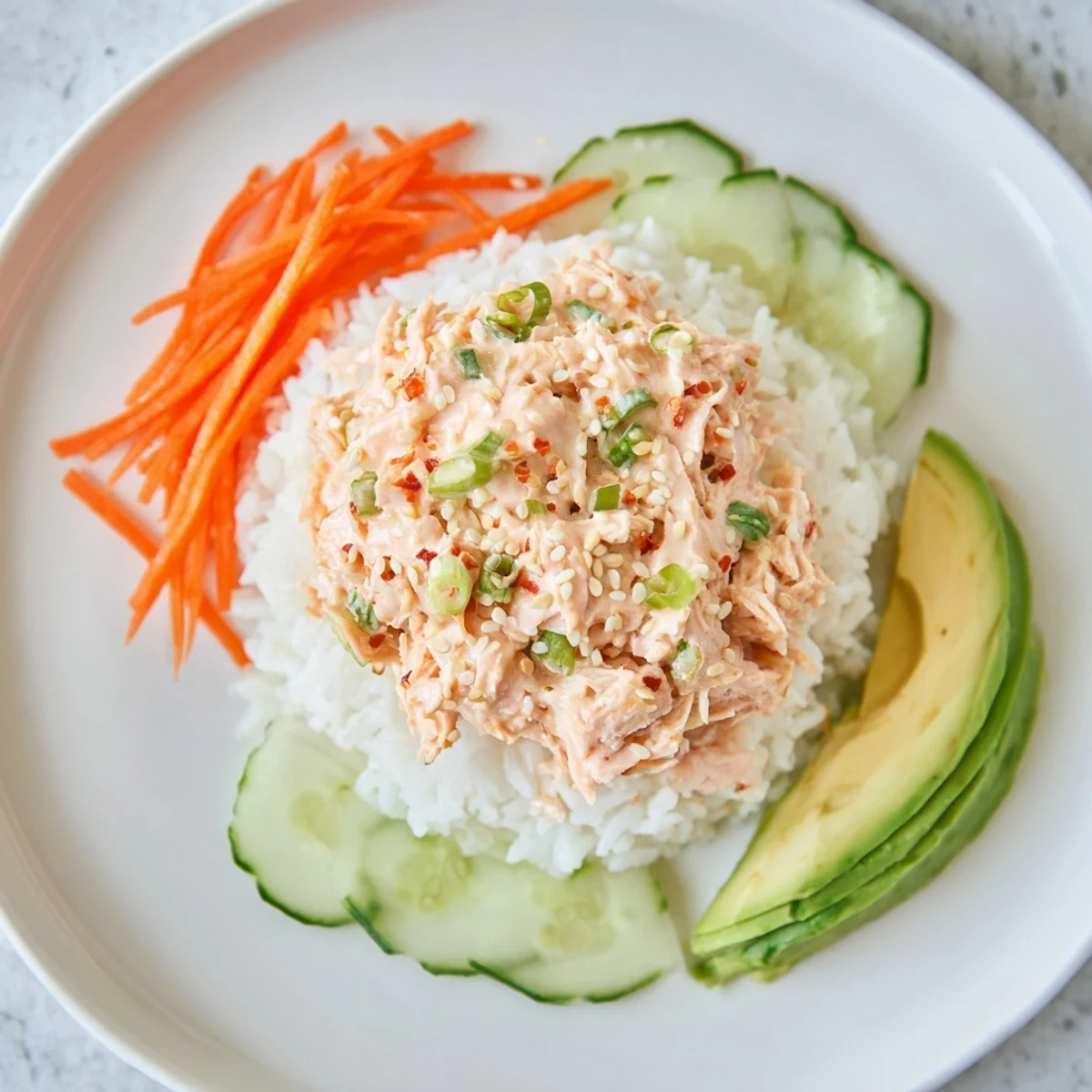 Perfectly plated Spicy Canned Salmon Rice Bowl showcases creamy salmon and fresh cucumber slices.