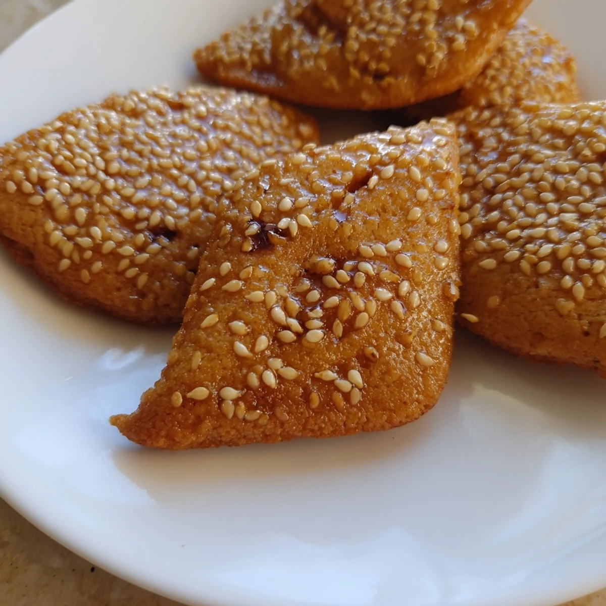 Close-up of freshly cooked, aromatic Tunisian Makroudh cookies, showcasing a sweet date filling and sesame seeds.