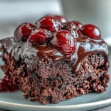 Moist, chocolatey Cherry Cola poke cake layered with pudding and cream.