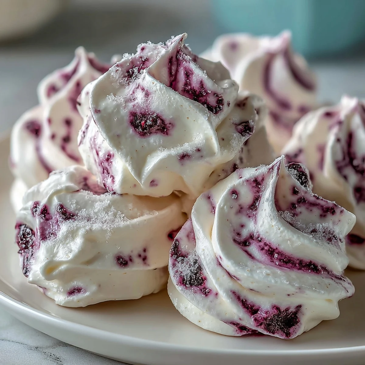 Four egg whites beaten into glossy peaks for Black Currant Meringues with a marbled purple swirl.