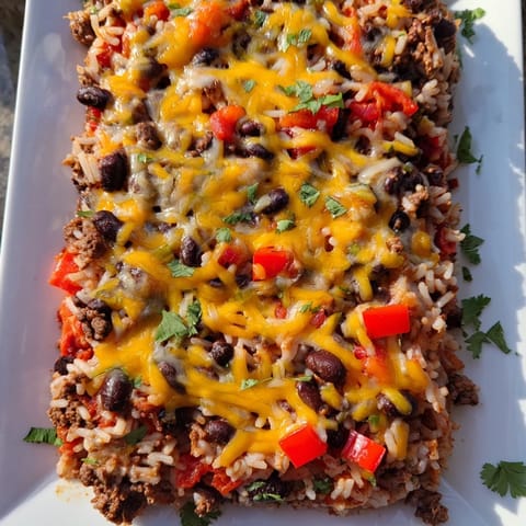 A delicious, cheesy Tex-Mex Beef & Rice Casserole, loaded with savory beef, beans, and fresh cilantro.