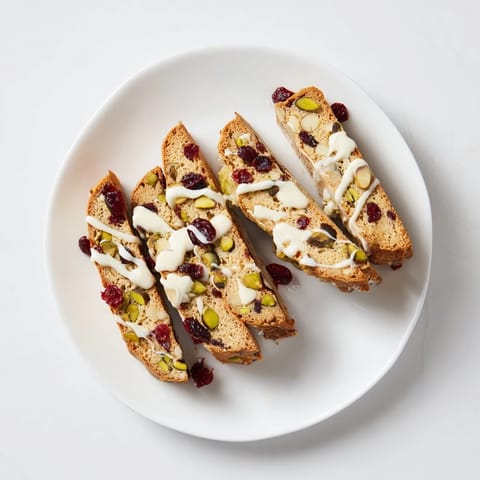 Drizzled white chocolate accents these cranberry pistachio biscotti, a perfect Italian cookie for coffee or gifting.