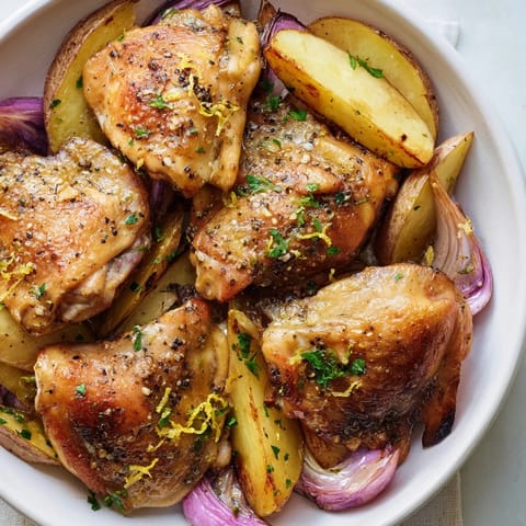Sheet pan Greek Lemon Chicken and Potatoes, perfectly crisp chicken thighs atop tender wedges, ready to eat.