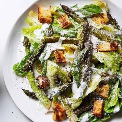 Freshly shaved Parmesan garnishes the vibrant Roasted Asparagus Caesar Salad, drizzled with creamy, tangy yogurt dressing.