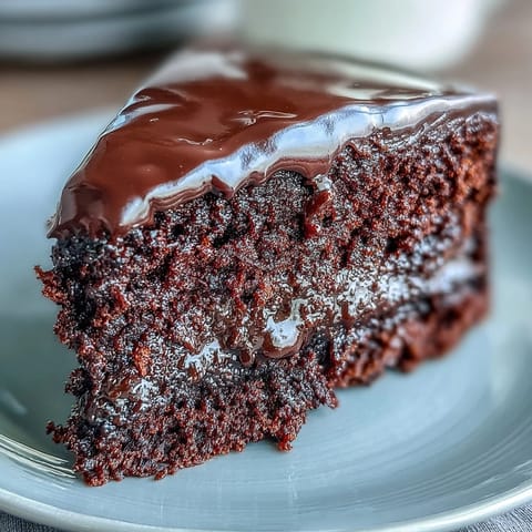 A fully frosted Easy Chocolate Fudge Cake sits ready to slice, perfect for celebrations or an indulgent teatime treat.