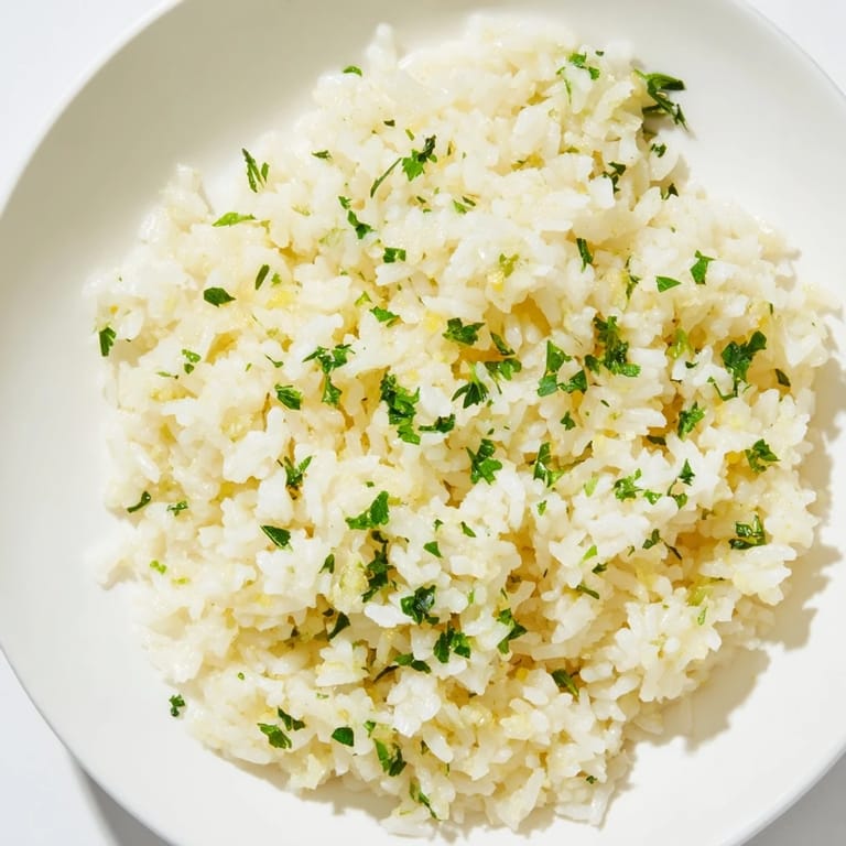 A close-up view of steaming Garlic Butter Rice, showcasing the fluffy texture and aromatic garlic scent.