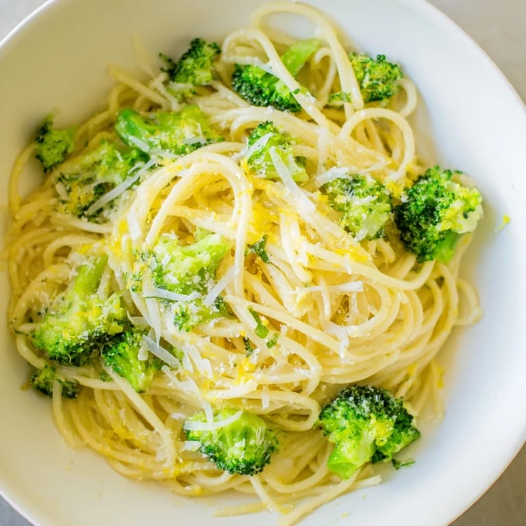 A close-up of one-pot lemon broccoli pasta shows al dente spaghetti coated in a creamy garlic sauce with fresh basil garnish.  
