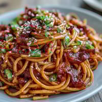 Creamy Gochujang Butter Pasta with garlic and sesame, a vibrant Korean-inspired dish served in a white bowl.