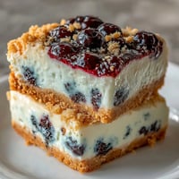 Creamy no-bake lemon blueberry cheesecake bars swirled with vibrant fruit.